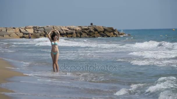 Молодая девушка прогуливается вдоль берега моря в медленном движении — стоковое видео