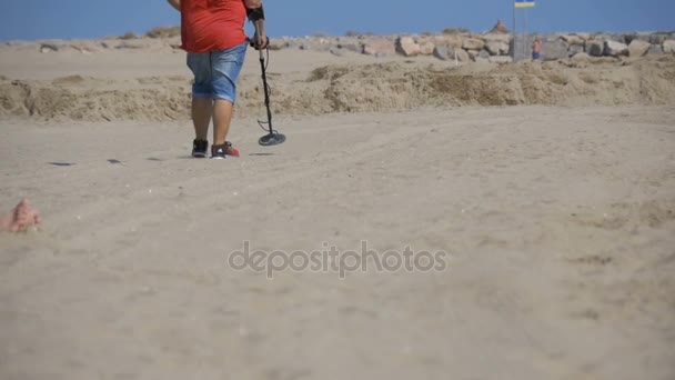 Adam bir Metal dedektörü ile Sandy plaj boyunca deniz kıyısı üzerinde yürür. Ağır çekim — Stok video
