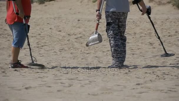 Two Mans with a Metal Detector Walks along a Sandy Beach on the Seashore. Moción lenta — Vídeo de stock