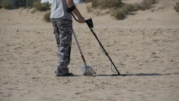 Mann mit Metalldetektor läuft an einem Sandstrand am Meer entlang. Zeitlupe — Stockvideo