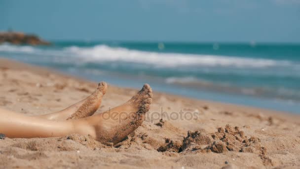 Benen van vrouw liggend op het strand in de buurt van de zee in Slow Motion — Stockvideo