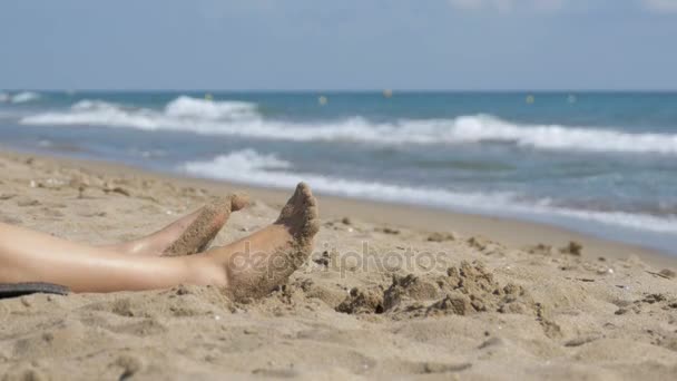 Lábak a nő feküdt, strandon, a tenger közelében — Stock videók