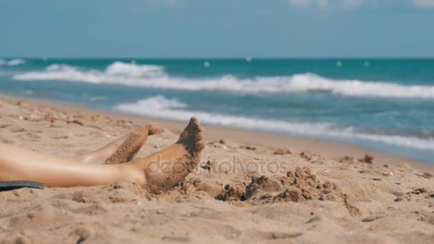Nogi kobieta leżąc na plaży, w pobliżu morza — Wideo stockowe
