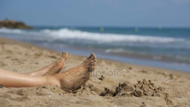 Ноги жінка лежачи на пляжі на березі моря в уповільненому Русі — стокове відео