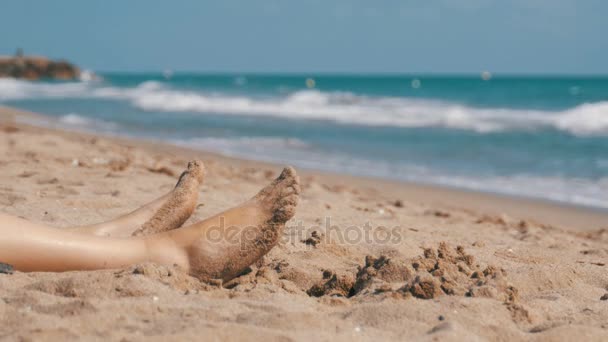 Ноги жінка лежачи на пляжі на березі моря — стокове відео