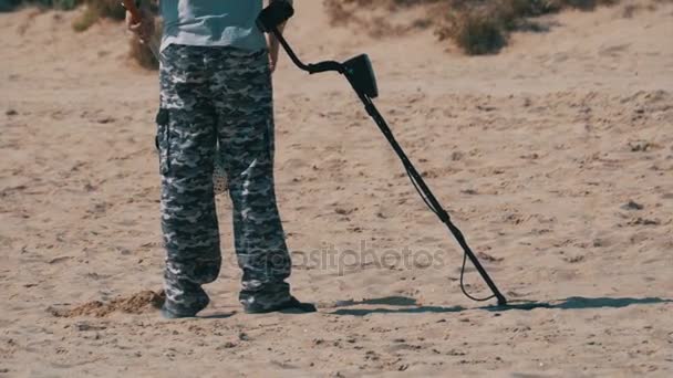 Άνθρωπος με έναν ανιχνευτή μετάλλων που περπατά κατά μήκος μια αμμώδης παραλία στην παραλία — Αρχείο Βίντεο