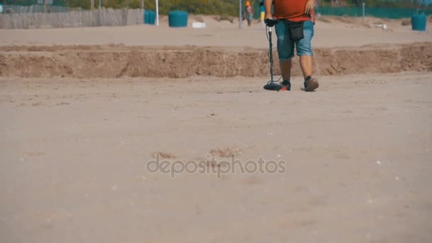 Mann mit Metalldetektor läuft an einem Sandstrand am Meer entlang. Zeitlupe — Stockvideo