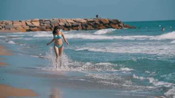 Menina em maiô corre ao longo da costa do mar na praia em Slow Motion — Vídeo de Stock