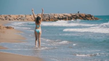 Ağır çekimde sahilde deniz kıyısında kız mayo içinde çalışır