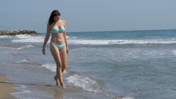 Chica joven camina a lo largo de la playa de la costa del mar en cámara lenta — Vídeos de Stock