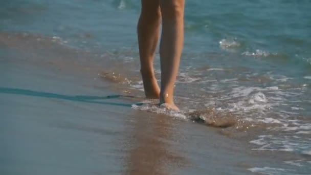 Dziewczyna w kostiumie kąpielowym biegnie wzdłuż brzegu morza na plaży w zwolnionym tempie — Wideo stockowe