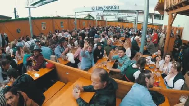 Pessoas bêbadas na mesa celebram Oktoberfest em um grande bar de cerveja na rua. Baviera, Alemanha — Vídeo de Stock