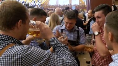 Bir büyük bira bar bira bardağı ellerinde ile içinde sarhoş mens Oktoberfest kutlamak. Bavyera, Almanya.