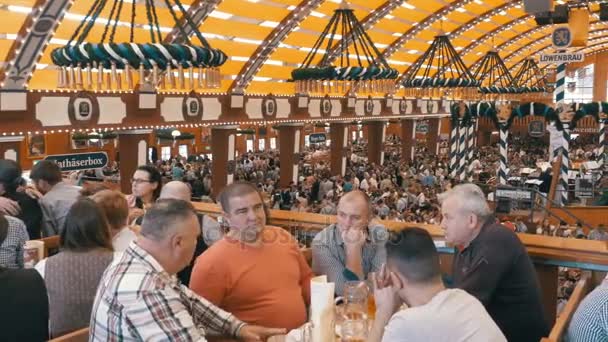 Publikum af berusede mennesker fejrer Oktoberfest inde i et stort øltelt. Bayern, Tyskland – Stock-video