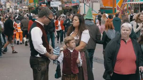 Gente con trajes nacionales bávaros caminando por la calle del festival Oktoberfest. Munich, Alemania — Vídeos de Stock