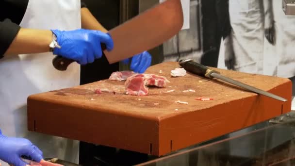 Slaktaren skära rått kött med stor kniv i marknaden La Boqueria. Barcelona. Spanien — Stockvideo