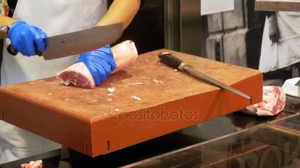 Slaktaren skära rått kött med stor kniv i marknaden La Boqueria. Barcelona. Spanien — Stockvideo