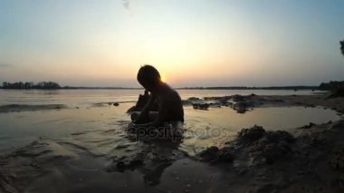 Küçük çocuk yapılar bir kum kale günbatımında siluet. Timelapse