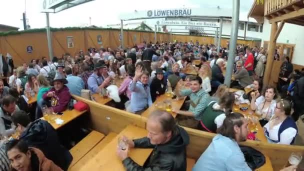 Dronken mensen aan de tafel vieren Oktoberfest in een grote Biercafé op straat. Beieren, Duitsland — Stockvideo