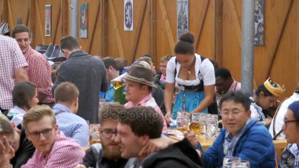 Pessoas bêbadas na mesa celebram Oktoberfest em um grande bar de cerveja na rua. Baviera, Movimento Lento — Vídeo de Stock