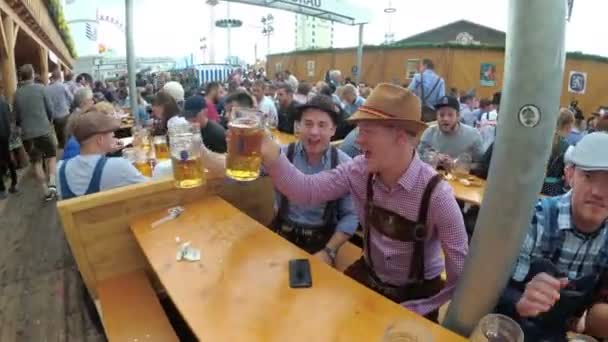 Betrunkene am Tisch feiern Oktoberfest in einer großen Bierbar auf der Straße. Bayern, Deutschland