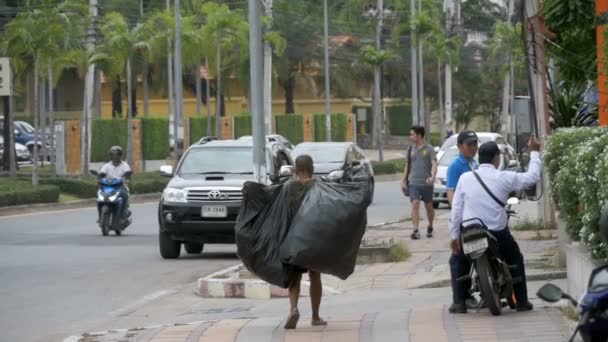 Uomo asiatico con grandi sacchi della spazzatura cammina lungo il marciapiede al rallentatore. Thailandia. Pattaya — Video Stock