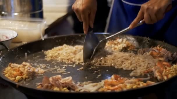 Азіатський безпритульних продовольства. Морепродукти, рису локшиною з яйцем приготування їжі на великій сковороді. Повільний рух. Таїланд — стокове відео