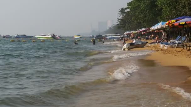 Береговая линия пляжа. Люди купаются в море, катаются на водных аттракционах, волны бьются по песчаному берегу. Таиланд. Паттайя . — стоковое видео