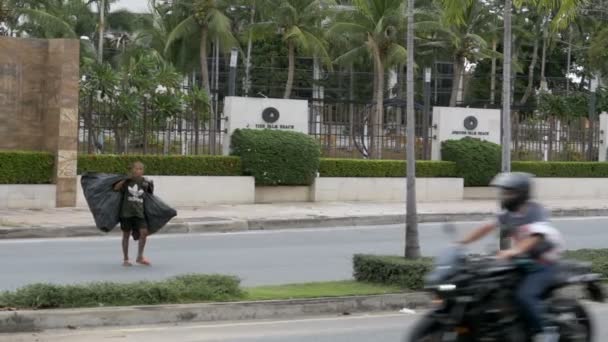 Ein asiatischer Mann mit einem großen Müllsack überquert in Zeitlupe die Straße. Thailand, Pattaya. — Stockvideo