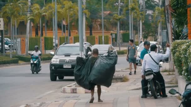 Азіатських людині з великий сміттєвий сумки прогулянки вздовж тротуару в повільному темпі. Таїланд. Паттайя — стокове відео