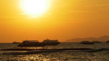 Kırmızı günbatımı dalgalar üzerinde sallanan siluet tekne ile denizde. Tayland. Pattaya