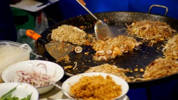 Ázsiai utcai élelmiszer. Tenger gyümölcsei, rizs tészta tojás főzés egy nagy serpenyőben. Thaiföld. — Stock videók