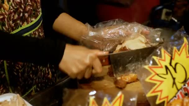 Woman Vendor at a counter cuts a fried chicken into pieces. — Stock Video