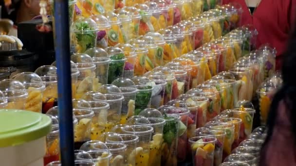 Escaparate con frutas en vasos de plástico en el mercado nocturno en la playa de Jomtien. Pattaya, Tailandia — Vídeo de stock