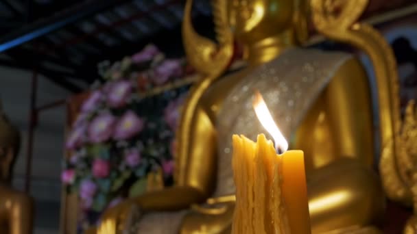 Candle brännskador på bakgrunden av statyn gyllene Buddha i templet. Pattaya. Thailand — Stockvideo