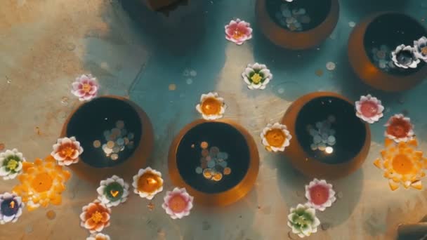 Bunte Kerzen in Lotusform schweben in einem buddhistischen Tempel auf dem Wasser. Thailand. — Stockvideo