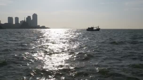 Silhouette di una barca da pesca in mare contro un abbagliamento di un sentiero soleggiato. Thailandia. In Asia. Pattaya . — Video Stock