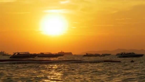Vörös naplemente csónakokkal imbolygott a hullámok a tengerparton. Thaiföld. Pattaya — Stock videók