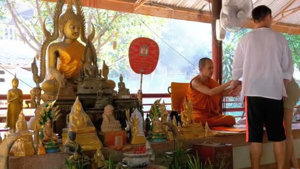 Mönch knotet den Touristen im buddhistischen Tempel des Paradieses und der Hölle ein Seil oder Band. Thailand — Stockvideo