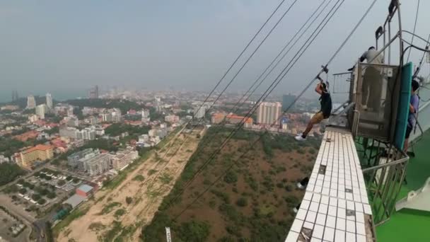 Skok z věže města Pattaya. Člověk jde dolů kabel ze střechy. Thajsko — Stock video