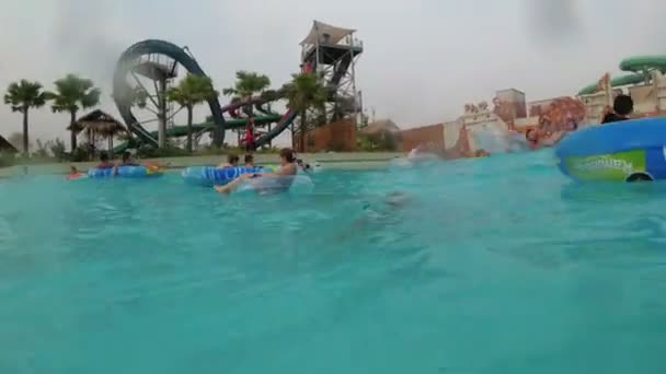 Vista subaquática de pessoas descansam e nadam em círculos infláveis na piscina — Vídeo de Stock