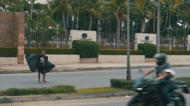 Homem asiático com grandes sacos de lixo a atravessar a rua em câmara lenta. Tailândia, Pattaya . — Vídeo de Stock