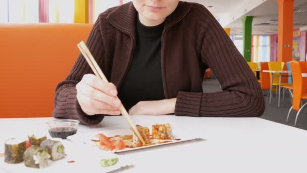 Женщина ест суши-роллы с палочками в японском ресторане — стоковое видео
