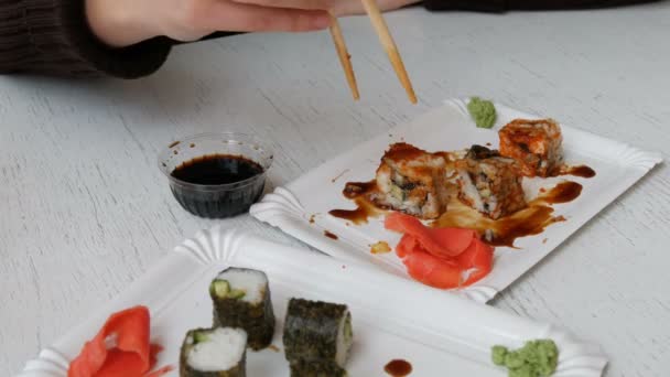 Mujer come rollos de sushi con palillos en un restaurante japonés — Vídeo de stock