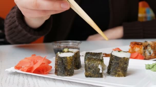 在日本餐厅, 女孩用筷子吃寿司卷 — 图库视频影像