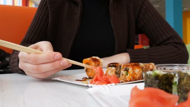 Женщина ест суши-роллы с палочками в японском ресторане — стоковое видео
