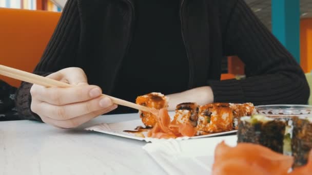 Meisje eet Sushi Rolls met stokjes in een Japans Restaurant — Stockvideo