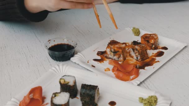 Chica come rollos de sushi con palillos en un restaurante japonés — Vídeos de Stock