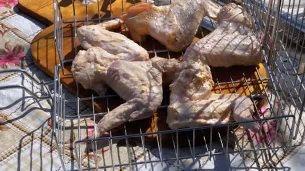 Alitas de pollo crudas en la parrilla está sobre la mesa en el pueblo — Vídeos de Stock