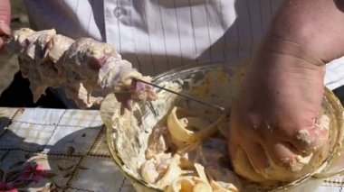 Şişman adam Marine çiğ et şiş kebap niteliğine için bir şiş koyar. Ağır çekim